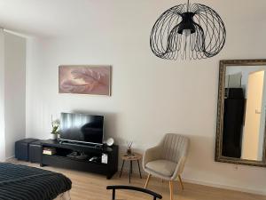 a living room with a tv and a chair and a mirror at Soliq Stay App in Tuzla +5 photos