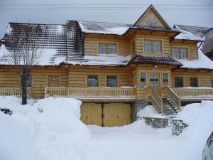 a wooden house with snow in front of it at Drevenica Gabriel in Ždiar