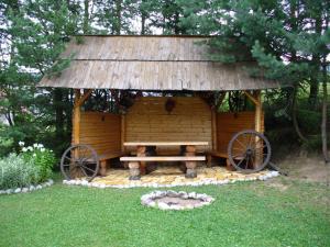 a wooden hut with a bench andokedoked wheels in the grass at Drevenica Gabriel in Ždiar