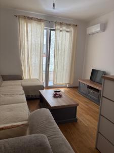 a living room with a couch and a table and a tv at Apartment MareMare Budva in Rafailovici