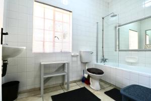 a white bathroom with a toilet and a sink at Cottage on 10th in Gqeberha