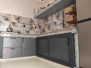 a kitchen with gray cabinets and a marble wall at Oualidia in Oualidia