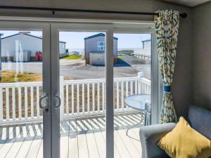 a sliding glass door to a deck with a chair at Peachy in Heysham