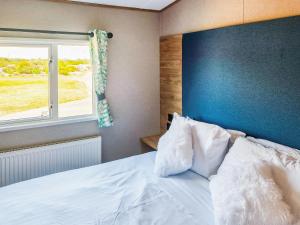 a bedroom with a bed with a blue headboard and a window at Peachy in Heysham