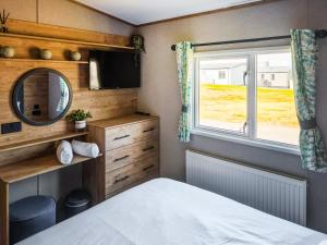 a bedroom with a bed and a mirror and a window at Peachy in Heysham