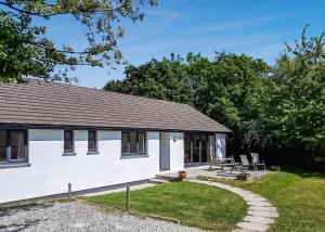 a white cottage with a patio and grass at Eastcott Lodges in North Tamerton