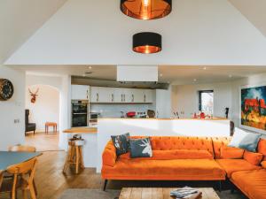 a living room with an orange couch and a kitchen at Strathspey Lodge in Duthil