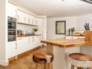 a kitchen with white cabinets and wooden counter stools at Strathspey Lodge in Duthil +27 photos
