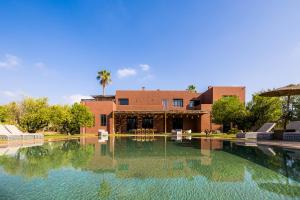 ein Haus mit einem Swimmingpool vor einem Gebäude in der Unterkunft Fellah Hotel in Marrakesch