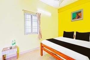 a bedroom with a bed with yellow walls and a window at Hotel O by OYO LA VGA RESIDENCY in Kottakupam +21 photos
