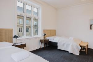 a bedroom with three beds and two windows at Nomad Hotel - Frederiksberg in Copenhagen