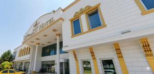 a white building with a yellow car in front of it at Ottoman Hotel Sakarya in Sakarya