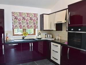 a kitchen with purple cabinets and a window with a curtain at Mountshade in Finzean