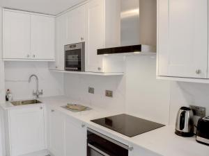 a white kitchen with white cabinets and a sink at Morton Loft in Hathersage