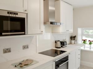 a white kitchen with white cabinets and a microwave at Morton Loft in Hathersage