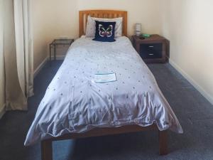 a bed with a gray comforter with a butterfly pillow at Cairn View in Strachan