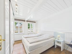 a white bedroom with a bed and a window at Min aran in Oevenum