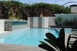 a swimming pool in a villa with a stone wall at Le Frangipanier - Appartement de luxe 3 chambres, 3 sdb, Péreybère in Pereybere