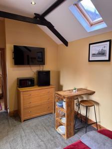 a living room with a tv and a table and a desk at Holywell Grange Farm in Whitley Bay