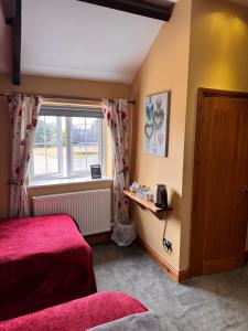 a bedroom with a red bed and a window at Holywell Grange Farm in Whitley Bay