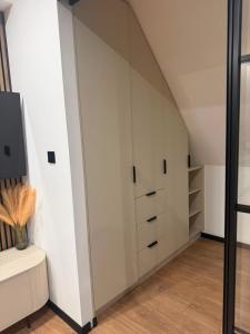a room with white cabinets and a tv at Apartament Zamkowy Zakątek in Lidzbark Warmiński