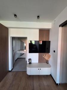 a living room with a white cabinet and a tv on the wall at Apartament Zamkowy Zakątek in Lidzbark Warmiński