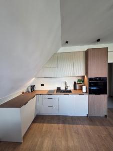 a kitchen with white cabinets and a black refrigerator at Apartament Zamkowy Zakątek in Lidzbark Warmiński