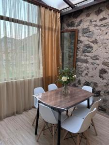 a dining room table with white chairs and a vase of flowers at Linet Apartament in Goris