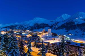 a town in the snow at night with snow covered mountains at Rifugio del Piemont in Villaretto