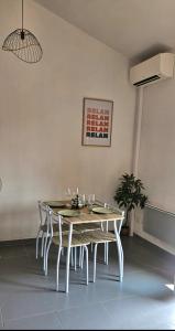 a dining room with a white table and chairs at Appartement près des Grands Buffets climatisé in Narbonne