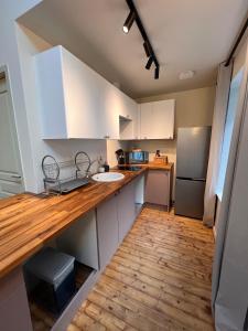 a kitchen with white cabinets and a wooden counter top at appartement chaleureux in Honfleur