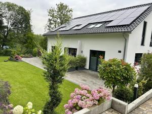 a white house with solar panels on the roof at Moderne 1-Zimmer-Gästewohnung im Neubau mit schönem Garten in Pronstorf