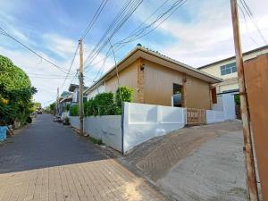 a house with a white fence next to a street at Gn story love บ้านเกาะล้าน 小珊瑚岛班泳池别墅 in Ko Larn