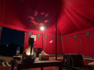 a red tent with a lamp on a table at Waatad in Irbid