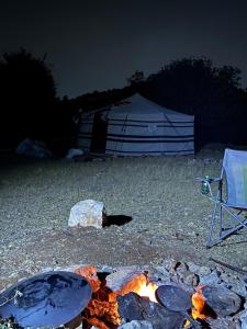 a fire pit with a tent in the background at night at Waatad in Irbid +40 photos