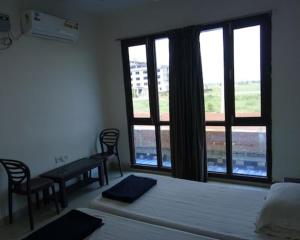 a bedroom with two beds and a table and a window at Hotel Tanman Continental, Rajgir in Rājgīr Kund