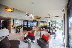a living room with chairs and a dining room and a kitchen at Lodge by the beach - Luxury, Beach access, Ocean views, Private chef in Kaiteriteri