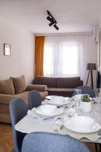 a living room with a table and chairs and a couch at UrApartment in Prizren