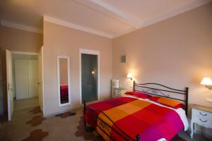 ローマにあるAlloggio Quiritiのベッドルーム1室(カラフルな毛布付きのベッド1台付)