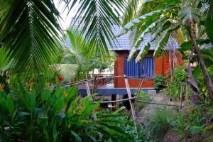 a house in the middle of a garden with palm trees at Homestay Nam Hàm Luông in Ben Tre