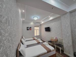a bedroom with two beds and a table and a tv at Bekh House SAM in Samarkand