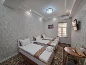 a room with three beds and a table and a table sidx sidx sidx at Bekh House SAM in Samarkand