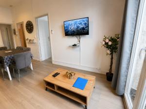 a living room with a table and a tv on the wall at Cosy & Clim Parfait jusqu'à 6 voyageurs bus gare shopping centre in Béziers