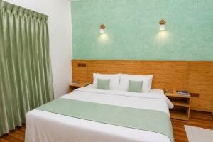 a bedroom with a large white bed and a green wall at Turtle Maldives - Your Gateway to the Beach & Marine Adventures Await! in Omadhoo