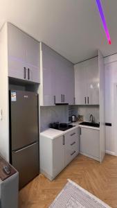 a kitchen with white cabinets and a stainless steel refrigerator at Capital city in Shymkent