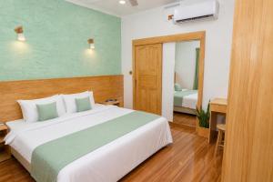 a bedroom with a large white bed and a mirror at Turtle Maldives - Your Gateway to the Beach & Marine Adventures Await! in Omadhoo