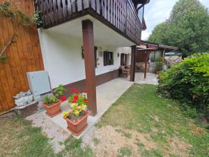 a house with two pots of flowers in a yard at Apartma Dajana in Lokve