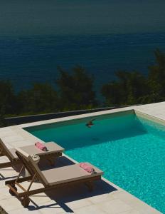 a swimming pool with a chaise lounge and a chair at Dream Tricule in Sviniţa