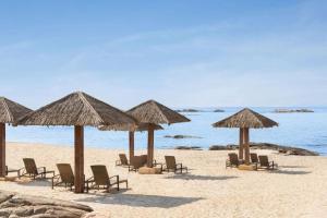 a group of chairs and umbrellas on a beach at Today House Suites 3 in Salalah