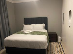 a bed with a black headboard in a bedroom at Leeba Apartments in Maseru